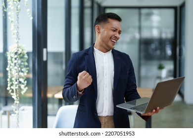 Portrait Of An Asian Male Business Owner Standing With A Computer Showing Happiness After A Successful Investment.