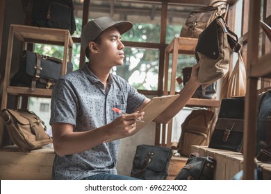 Portrait Of Asian Male Business Owner Check The Quality Of His Product At Bag Store