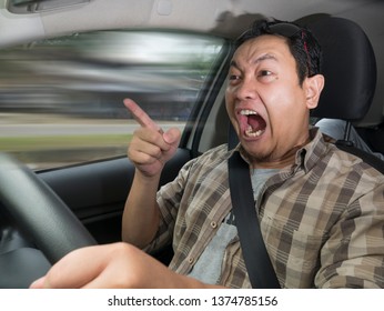 Portrait of Asian male driver mad of other car criver, speeding his car with anger dangerously,  mischievous reckless way of driving concept with motion blur