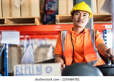 Portrait Of Asian Male Driver Sitting Driving On Forklift Truck Looking At Camera In The Warehouse Distribution. Men At Work For Logistic Shipping Career.