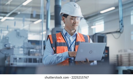 Portrait of an Asian Male Engineer in Orange Safety Vest Working on Laptop Computer at Electronic Manufacturing Factory. Technician Working on Daily Tasks and Research and Development Data. - Powered by Shutterstock