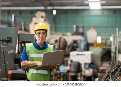 Portrait Of Asian Male Factory Worker Working With Laptop Computer In The Industry Factory. Male Engineer Working With Laptop Computer In The Factory