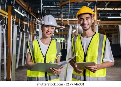 Portrait Of Asian Male And Female Industrial Worker Working In Factory. Attractive Manufactory Industry Engineer People Wear Helmet And Look At Camera At Manufacturing Plant Warehouse With Happiness.
