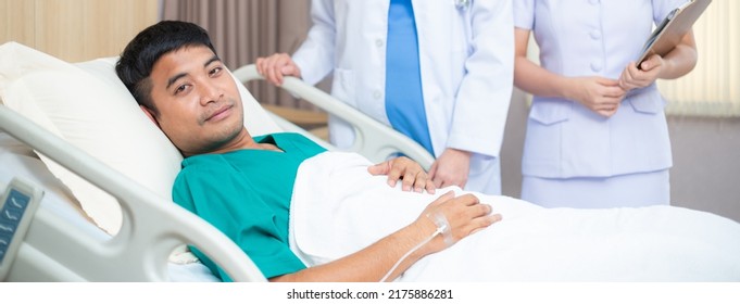 Portrait Of Asian Male Patient Getting Better From Fully Recovery Lying On Bed In The Hospital Ward Looking At Camera. Medical And Healthcare Insurance Concept