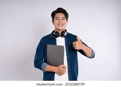 Portrait of Asian male student wearing cable and headphones , using laptop and  posing on white background - Powered by Shutterstock