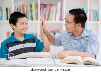 Portrait Of An Asian Male Teacher Doing High Five With His Student While Studying Together In The Library