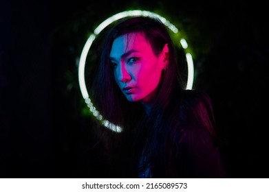 Portrait Of An Asian Man Against The Background Of A Circular Lamp In The Studio With Neon Light. 