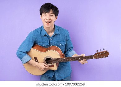 Portrait of Asian man in blue shirt posing on purple background