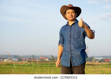 Portrait Of Asian Man Farmer Wears Hat, Thumbs Up. Smiles. Feels Confident. Concept : Happy Farmer. Agriculture Occupation.  Copy Space For Adding Text Or Advertisement.