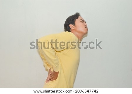 portrait of asian man groaning in pain while holding his back waist. Gestures of people who are injured in the spine or pinched nerves. Piriformis Syndrome or Hernia Nucleus Pulposus pain illustration