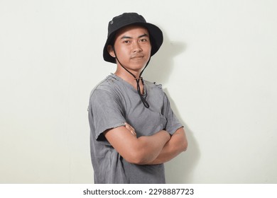 portrait of an Asian man with a happy face, smiling or laughing while looking at the camera. Indonesian man wearing hat, torn, dirty and shabby t-shirt on isolated white background. - Shutterstock ID 2298887723