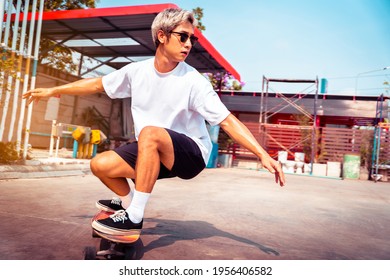 Portrait Asian Man Having Fun Playing Surfboards Or Surf Skate Outdoors In The City Streets