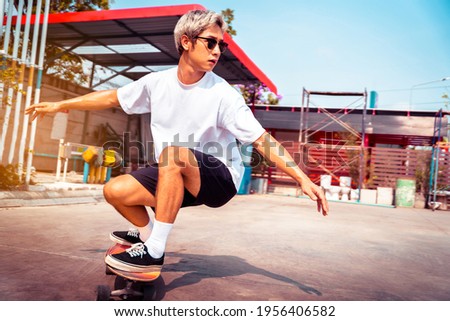Portrait Asian man having fun playing surfboards or surf skate outdoors in the city streets