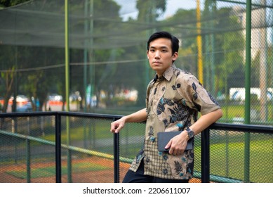 Portrait Of Asian Man Model Wearing Batik Shirt From Indonesian Holding Clutch Bag In Outdoor 