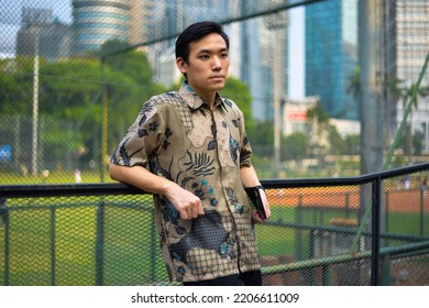 Portrait Of Asian Man Model Wearing Batik Shirt From Indonesian Holding Clutch Bag In Outdoor 