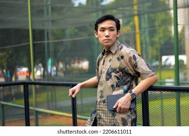 Portrait Of Asian Man Model Wearing Batik Shirt From Indonesian Holding Clutch Bag In Outdoor 