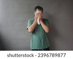 Portrait of asian man on green shirt using hand towel to wiped sweat on his face show tired after work on grey background