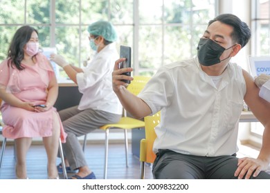 Portrait Of Asian Man Selfie By Phone At While Getting Covid Vaccine In Clinic Or Hospital, With Hand Nurse Injecting Vaccine To Get Immunity For Protect Virus. People Wearing Protective Mask.