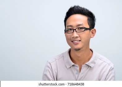 Portrait Of Asian Man Smiling And Looking At Camera, Standing Isolated On Plain Background.