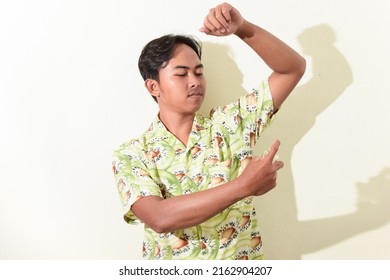 Portrait Of Asian Man Spraying Perfume On His Body. Indonesian Man In Hawaiian Shirt On White Background Isolated. Cool And Handsome Asian Man Portrait