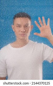 Portrait Of Asian Man Standing Behind Bubble Wrap And Wiping With Hand