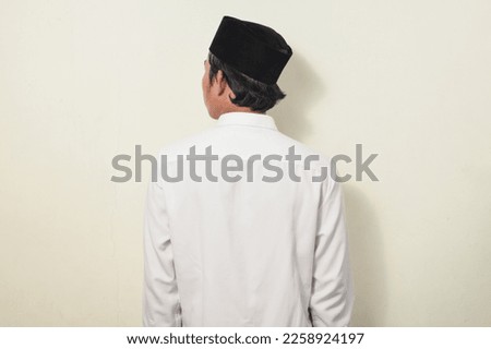 portrait of asian man turning over. asian man standing back view. Indonesian man wearing cap and white shirt on isolated white background.