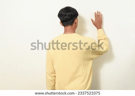 portrait of asian man turning over. asian man standing back view. Indonesian man wearing yellow shirt on isolated white background. greeting poses or waving hands