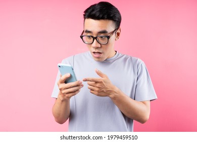 Portrait of Asian man using smartphone on pink background - Powered by Shutterstock