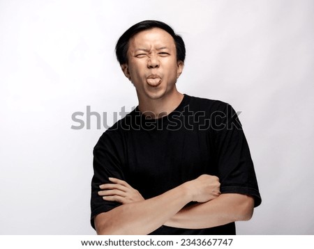A portrait of an Asian man wearing a black t-shirt, standing and looking mocking or taunting, isolated on a white background.