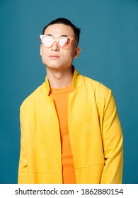 Portrait Asian Man Wearing Glasses Orange Tshirt Yellow Jacket Blue Background Cropped View Model