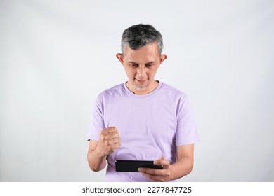 Portrait of Asian Man wearing purple tshirt looks happy with the phone.
 - Shutterstock ID 2277847725