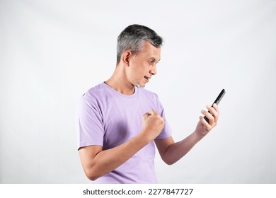 Portrait of Asian Man wearing purple tshirt looks happy with the phone.
 - Shutterstock ID 2277847727