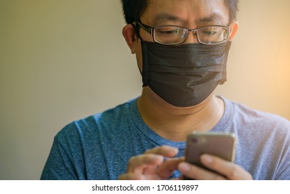 Portrait Asian man wears black medical mask and texting on smartphone, close up Asian man with eyeglasses, black short hair, eyes looking to smartphone, wears blue tshirt. - Powered by Shutterstock