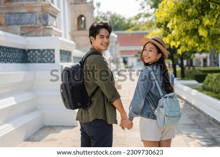 Portrait of Asian man and woman travel couple backpackers in relationship holding hands inside of buddhist temple on street in Bangkok, Thailand, Southeast Asia - healthy relationship travel concept