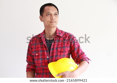Portrait Asian man, working age, handsome, dignified,concept senior engineer .He stood holding a yellow safety helmet at the level of his left body. wearing a red plaid shirt.Isolated white background Stock photo © 