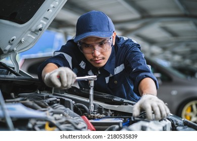 Portrait of an Asian mechanic checking the safety of a car. Maintenance of damaged parts in the garage. Maintenance repairs. Repair service concept.
