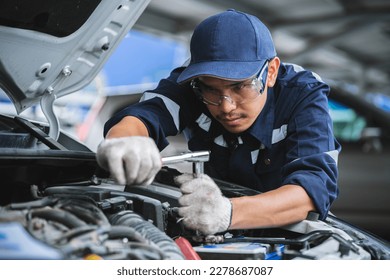 Portrait of an Asian mechanic checking the safety of a car. Maintenance of damaged parts in the garage. Maintenance repairs. Repair service concept. - Powered by Shutterstock