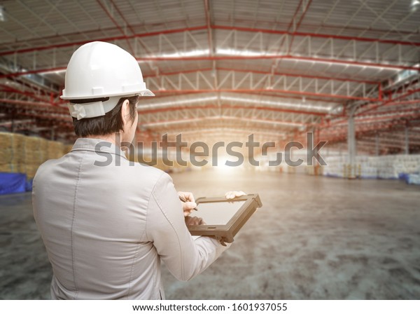 Portrait\
Asian men, staff, product counting Warehouse Control Manager\
Standing, counting and inspecting products in the warehouse\
,Interior of a modern warehouse ,clean and\
empty