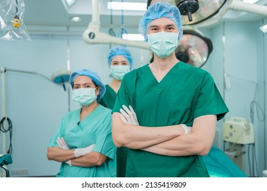 Portrait Of Asian Men Surgeon And Nurse With Medical Mask Standing With Arms Crossed In Operation Theater At A Hospital. Team Of Professional Surgeons. Healthcare, Emergency Medical Service Concept