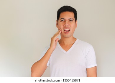Portrait of Asian men with worry eyes use hand touching his cheek , feelings pain from toothache. Tooth and mouth disease concept.