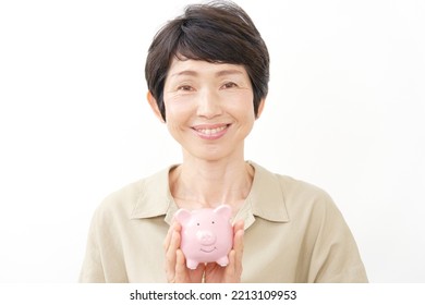 Portrait Of Asian Middle Aged Woman Smiling With The Piggy Bank In White Background