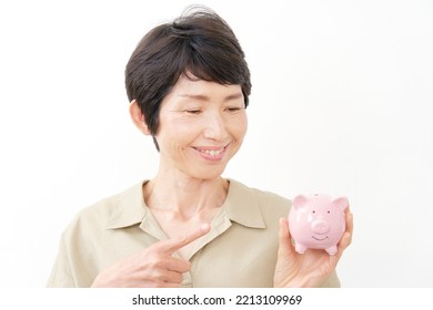 Portrait Of Asian Middle Aged Woman Smiling With The Piggy Bank In White Background