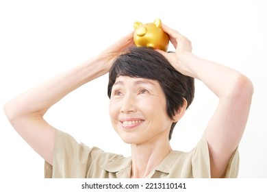 Portrait Of Asian Middle Aged Woman Smiling With The Piggy Bank In White Background