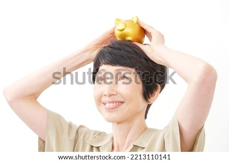 portrait of Asian middle aged woman smiling with the piggy bank in white background