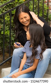 Portrait Of An Asian Mom Combing Her Daughters Hair.