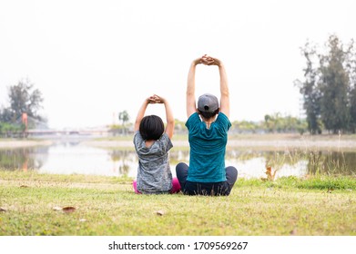 Portrait Asian Mother And Daughter Exercise In The Garden.Sporty Woman And Child Yoga Practice In The Public Park.Outdoor Relaxation And Happiness Family Time Concept.