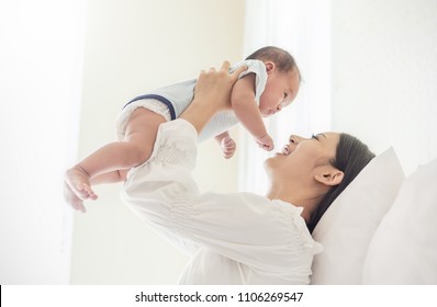 Portrait of asian mother lifting and playing with newborn baby, baby talking to mother. Health care family love together nursery lifestyle mother’s day concept