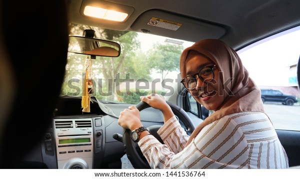 portrait of Asian Muslim hijab women facing the\
camera while driving a\
car