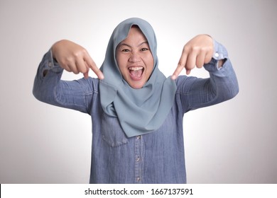 Portrait Of Asian Muslim Woman Surprised And Pointing Down Isolated On White