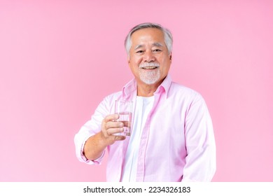 portrait of asian old man hand holding glass of water drinking smile wearing pink shirt and pink black background. - Powered by Shutterstock